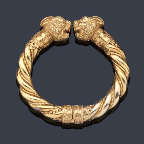 Brazalete con pareja de protomos 'cabeza de león' enfrentados con decoración de cordoncillo y rosetones, realizado en montura de oro amarillo de 18K.