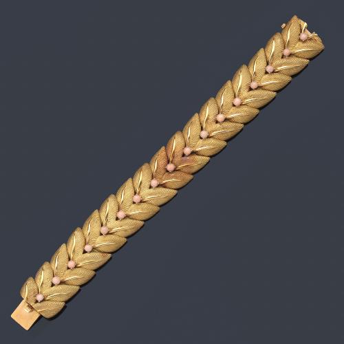  Pulsera con diseño vegetal con motivos esféricos de coral rosa al centro, en oro mate y brillo amarillo de 18K. Años '70.