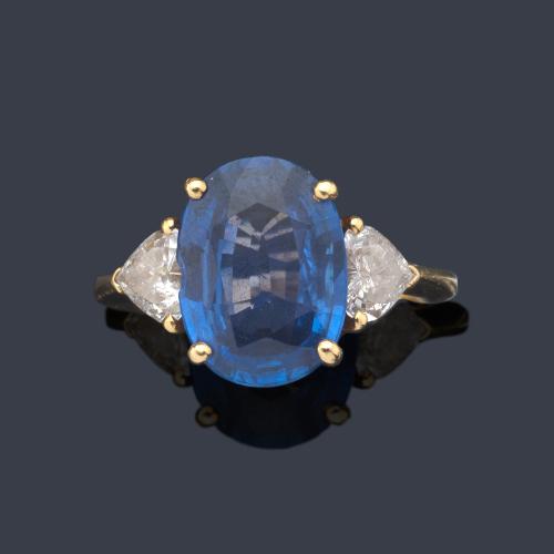  Anillo con zafiro talla oval de aprox. 5,08 ct con pareja de diamantes talla corazón, uno a cada lado.