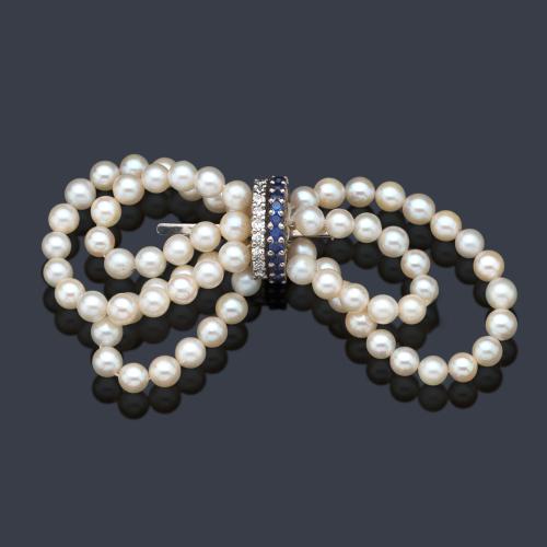  Broche con diseño de lazada con perlas de aprox. 5,02 - 5,04 mm con banda central de zafiros y brillantes sobre montura de oro blanco de 18K.