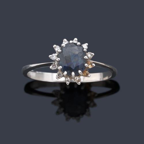 Anillo con zafiro talla oval de aprox. 0,90 ct con orla de brillantitos en montura de oro blanco de 18K.