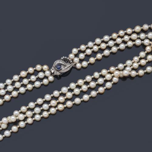  Collar con tres hilos de perlas australianas de aprox. 8,62 mm - 9,86 mm intercalado con perlitas de menor calibre, con broche vegetal con diamantes y un zafiro talla oval, en montura de oro blanco de 18K.