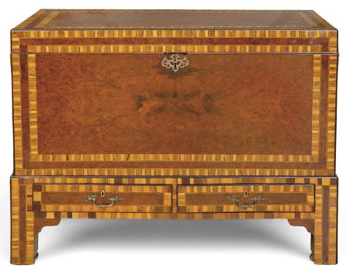  Chest on stand George III, 
Cómoda de cuerpo rectangular, chapada en nogal y raíz de nogal, con decoración de bandas de maderas contrastadas y filetes lineales.