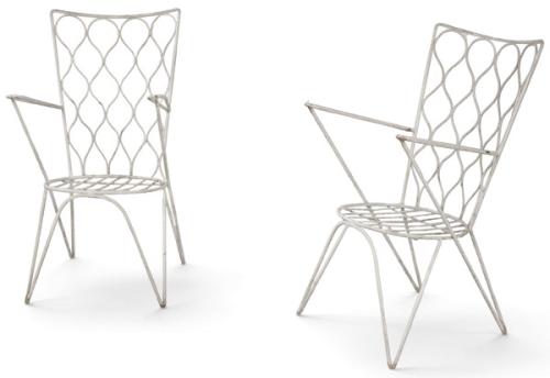  Pareja de sillones de jardín, en hierro pintado en blanco, con respaldo alto formado por retícula de varillas onduladas, asiento calado de varillas paralelas, brazos rectos con tirantes diagonales y patas divergentes. 