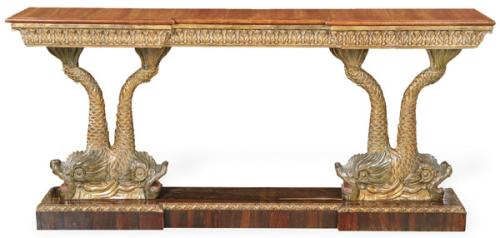  Consola estilo Imperio, con tapa rectangular recortada, con decoración de hojas de acanto talladas y doradas, sobre pedestales en forma de figuras de peces enfrentados pintados y dorados sobre plataforma. S. XX