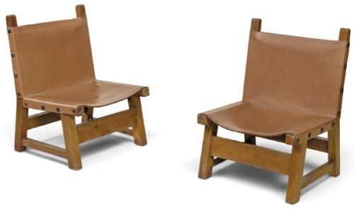  Pareja de butacas bajas con estructura de madera nogal y asiento y respaldo suspendidos en cuero.